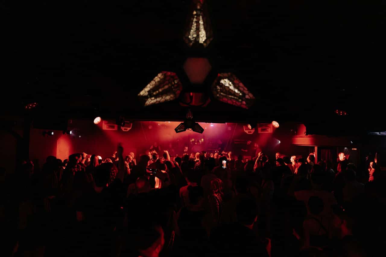 Red-lit Carousel dancefloor packed beneath the lighting rig